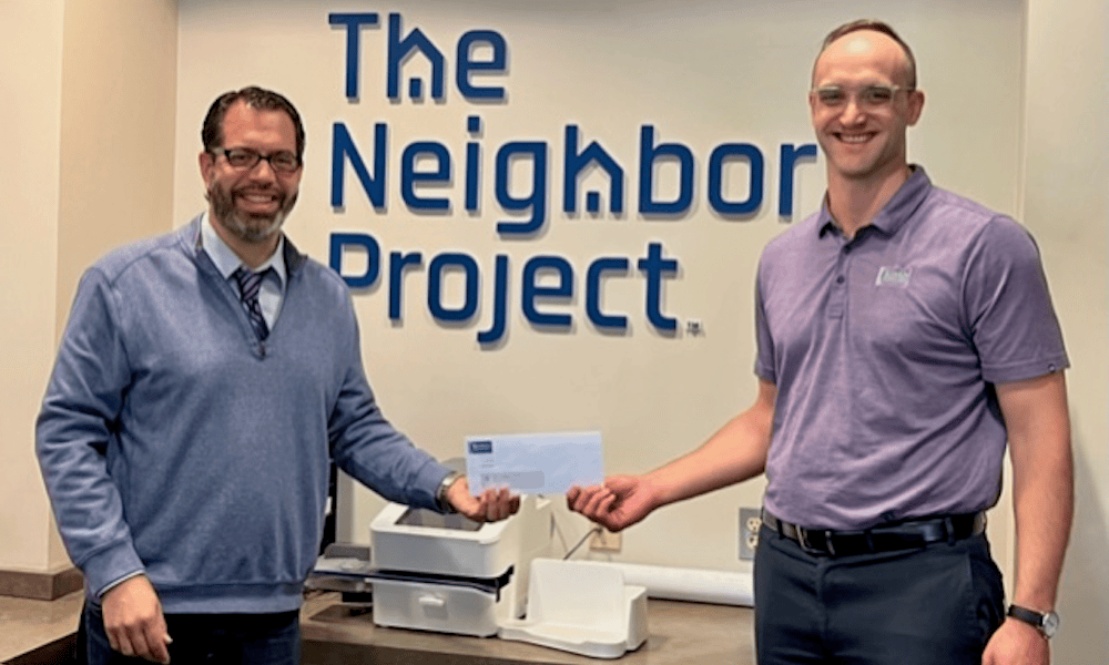 Pictured is Nick Knudtson presenting a $1,000 donation to Rick Guzman, Executive Director of The Neighbor Project.
